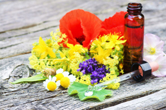 Blüten neben einem Bachblüten-Fläschchen: Tropfen sind die klassische Anwendung.