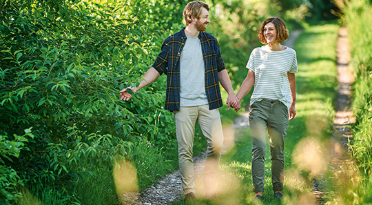 Paar geht in der Natur spazieren: Durch das Vitamin-B-Komplex-Tonikum haben sie wieder mehr Energie.